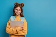 © MadMouse - Portrait of a schoolgirl in glasses holding a laptop against a blue background