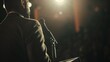 © JR-50 - A speaker addresses a large audience, bathed in the warm glow of a spotlight.