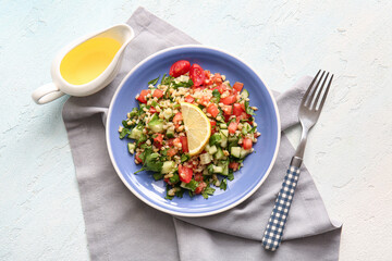Wall Mural - Plate with delicious tabbouleh salad and oil on light background