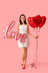 Wall Mural - Beautiful young woman with air balloons in shape of word LOVE and heart on pink background. Valentine's Day celebration