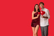 © Pixel-Shot - Young couple with air balloons in shape of heart on red background. Valentine's Day celebration
