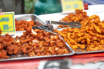 A table with two trays of food, one with chicken and the other with fish. The chicken is fried and the fish is also fried