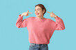 © Pixel-Shot - Beautiful young woman pointing at hearing aid on blue background