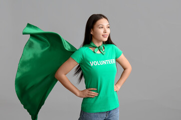 Young female volunteer in superhero cape on white background