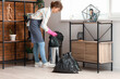 © Pixel-Shot - Young woman taking garbage bag from trash bin at home