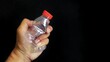 © Adeniadit - A man's hand squeezes an empty plastic bottle isolated on the black background.