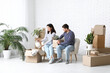 © Pixel-Shot - Young happy couple unpacking belongings on white sofa in their new house