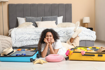 Wall Mural - Beautiful young happy woman unpacking summer clothes from suitcases at home