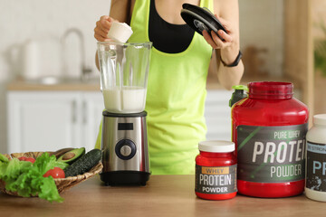 Poster - Sporty young woman making protein shake in blender at home, closeup