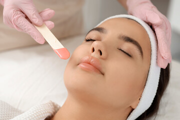 Wall Mural - Beautician with wax removing woman's hair in salon, closeup