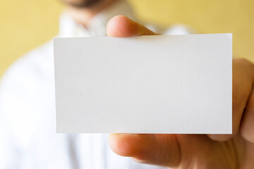 A white business card is in a man’s hand.