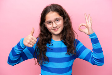 Wall Mural - Little girl isolated on pink background With glasses and doing OK sign