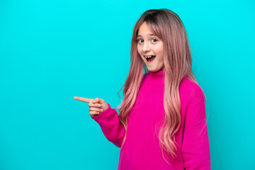 Canvas Print - Little girl with pink hair isolated on blue background surprised and pointing finger to the side