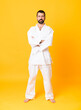 © luismolinero - Full-length shot of man over isolated yellow background doing karate keeping the arms crossed