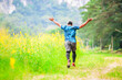 © STOCK PHOTO 4 U - Man Running Joyfully Through a Green Field with Yellow Flowers and Lush Trees in the Background