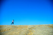 © STOCK PHOTO 4 U - Runner on a Vast Rocky Terrain Under Clear Blue Sky, Capturing the Essence of Freedom and Adventure in Nature