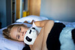 © evgeniia_1010 - A little blonde girl with a plush toy on a huge bed in an elegantly furnished hotel room.