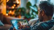 © NDmCX-Nic - A man relaxing at home on a cozy evening, watching a video on his laptop with warm lighting and plants in the background.