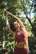 © insta_photos - Fit mindful young woman doing yoga exercises in green nature park. Authentic candid vertical photo or sporty Hispanic lady wearing sportswear meditating stretching standing in forest in sunny morning.