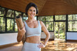 © insta_photos - Happy fit young Hispanic woman advertising yoga class. Sporty active lady yoga coach wearing sportswear holding mat standing in yoga gym studio with big windows looking at camera. Portrait. Copy space