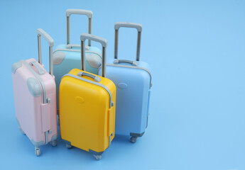 Different colorful suitcases on blue background. Tourism and vacation concept. Copy space for text.