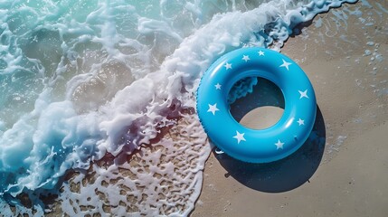 Wall Mural - Aerial view of a blue pool float with white stars on a sandy beach with waves rolling in, capturing a perfect summer moment by the sea.