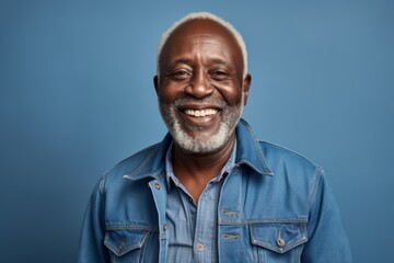 Portrait of a happy afro-american man in his 80s sporting a rugged denim jacket while standing against bare monochromatic room
