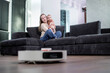 © volody10 - Happy mother playing with her baby son while robot vacuum cleaning floor at home