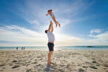 Poster - Beach, man holding girl in air and playful for vacation, weekend break and nature. Father swing daughter, relax and bonding at seaside, holiday and loving together for quality time, outdoor and smile