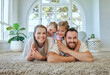 © peopleimages.com - Parents, portrait and piggyback on floor with children in house living room for bonding, love and happy. Family, girl and hug on ground with smile, face and carpet for relax, calm and peace together