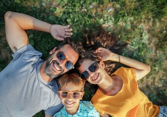 Wall Mural - A family of three, a man and two children, are laying on the grass and smiling