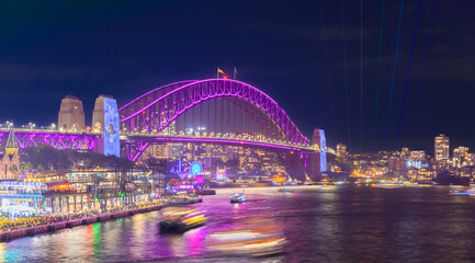 Wall Mural - Colourful Light show at night on Sydney Harbour NSW Australia. The bridge illuminated with lasers and neon coloured lights 