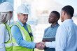 © Michael Cunningham/peopleimages.com - Building, handshake and men in deal for architecture, planning and agreement at construction site. Project, collaboration and civil engineering team shaking hands for urban development with welcome