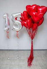 Wall Mural - silver balloons number 15 on a background of red hearts