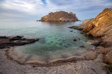 Small and idyllic cove on Amarilla beach in Aguilas, Region of Murcia, Spain, with transparent waters and the island of Fraile in the background