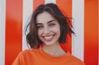© Fotograf - A woman with an orange shirt is smiling at the camera, conveying a sense of happiness and positivity