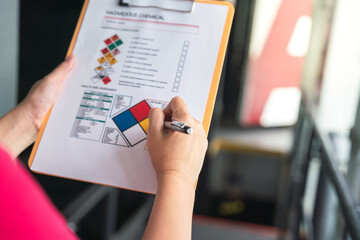 Wall Mural - action of a safety supervisor hand is checking on checklist of chemical and hazardous material form 