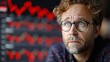 © Multiverse - A man with red hair and glasses looks worried as he stares at a stock market chart behind him, filled with red lines