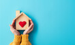 © zchris22 - Avere a cuore la propria casa. Due mani stringono una casetta di legno con un cuore dentro. Spazio per messaggio.