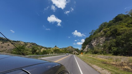 family traveling in a car walking on a road with a forest and mountains in the background on a sunny day on a trip on vacations