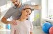 © Studio Romantic - Masseur therapist specializing in physiotherapy and rehabilitation, providing a neck massage or stretching session for a patient in a medical office. Holistic approach to physical medicine.