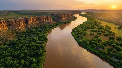 Wall Mural - Aerial View of Serene River Meandering Through Lush Landscape with Rocky Cliffs and Golden Sunset Reflected on the Water's Surface