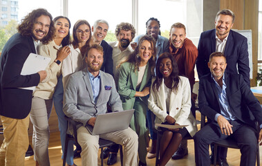 Group portrait of a happy smiling diverse business people at work in office. Staff and company employees men and women looking cheerful at the camera during a meeting or a conference.