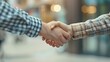 © Татьяна Макарова - Two people shaking hands, wearing casual clothing, on blurred outdoor background