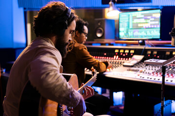 Aufkleber - Songwriter creating a new song with his guitar in control room, playing electro acoustic instrument and singing next to record producer. Young artist performing live, editing music on mixing console.
