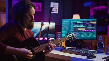 Leinwandbilder - Artist playing guitar and uses DAW software interface to create music, looking at mastering controls on computer screen. Musician recording soundtracks with tools, acoustical engineering. Camera B.