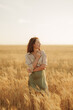 © arthurhidden - A tranquil scene of a young woman embracing herself, standing amidst a golden wheat field at sunset, conveying a sense of peace and self-love.