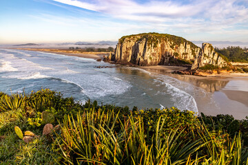 Guarita beach with waves, cliffs and winter fog over the trees