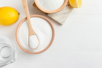 Baking soda, vinegar and lemons on white wooden table, flat lay. Space for text