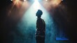© Artyom - Asian man stands under spotlight on stage, contemplating